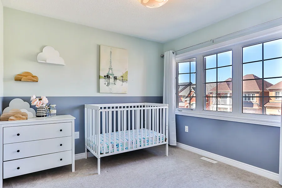 Kinderzimmer mit blauer Wand, weißem Gitterbett und Kommode